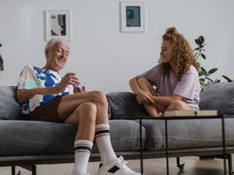 äldre man och ung kvinna som sitter i en soffa och pratar