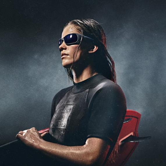 kvinna i glasögon som håller i surfingbräda