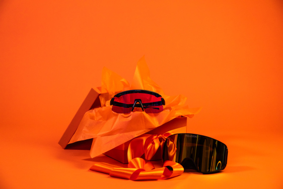 Oranssi lahjapaketti, jossa yhdet urheilulasit ja yhdet laskettelulasit